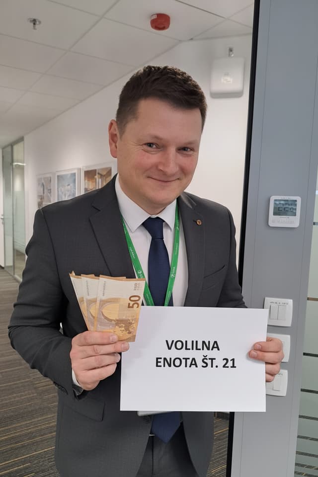 Na sliki je kandidat za člana sveta delavcev za volilno enoto št. 21. Mi prilagodiš sliko, da bo imel obleko s kravato in v roki list, kjer piše volilna enota št. 21