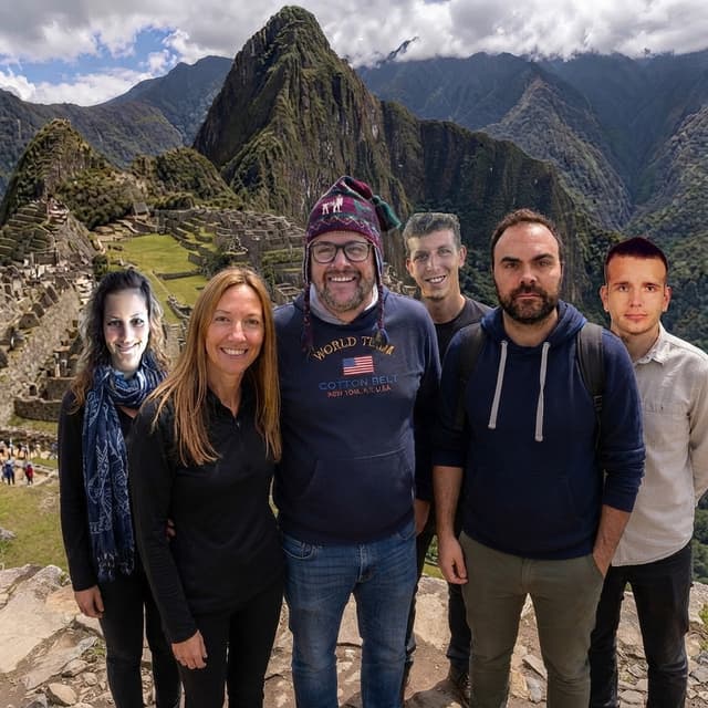Image 1 is the base photo: three people standing at Machu Picchu. Image 2 onward are reference photos of the additional people to add to Image 1.
Task: Add the people from the reference photos into Image 1 so they appear to be standing together with the three existing people, as if everyone was photographed at the same moment.
Strict rules:
- Do not change anything in Image 1 except the minimum needed to place the new people. The three existing people, their faces, clothing, poses, the Machu Picchu background, the sky, and the framing must stay exactly as they are.
- Preserve the exact facial identity of each added person from their reference photo: face shape, eyes, nose, mouth, skin tone, hairstyle, hair color, facial hair, and age. Do not beautify, smooth, de-age, slim, or alter their features in any way.
- Keep each added person's clothing, hair and body type as shown in their reference photo, unless the reference only shows the face, in which case use neutral clothing suitable for a sunny day at Machu Picchu. Do not add accessories, logos, text, or other details that are not in the references.
- Do not invent or add any new elements: no extra people, no new objects, no changes to the landscape, weather, or ruins.
- Match the lighting of Image 1 exactly: same sun direction, color temperature, brightness, and shadow direction and softness. Add natural contact shadows on the ground under each added person.
- Match the scale and perspective of Image 1: the added people must be proportionally sized to the existing people for their distance from the camera, standing on the same ground plane, with feet on the ground and no floating.
- Match the camera characteristics of Image 1: same resolution, sharpness, grain, depth of field, color grading, and lens look, so there is no visible difference between the original and added people.
- Place the new people naturally beside or between the existing people without overlapping or hiding their faces. Use relaxed, natural poses that fit a group photo.
- Photorealistic result only. No stylization, no painterly or CGI look.
Output: a single photorealistic group photo at the same aspect ratio and resolution as Image 1.